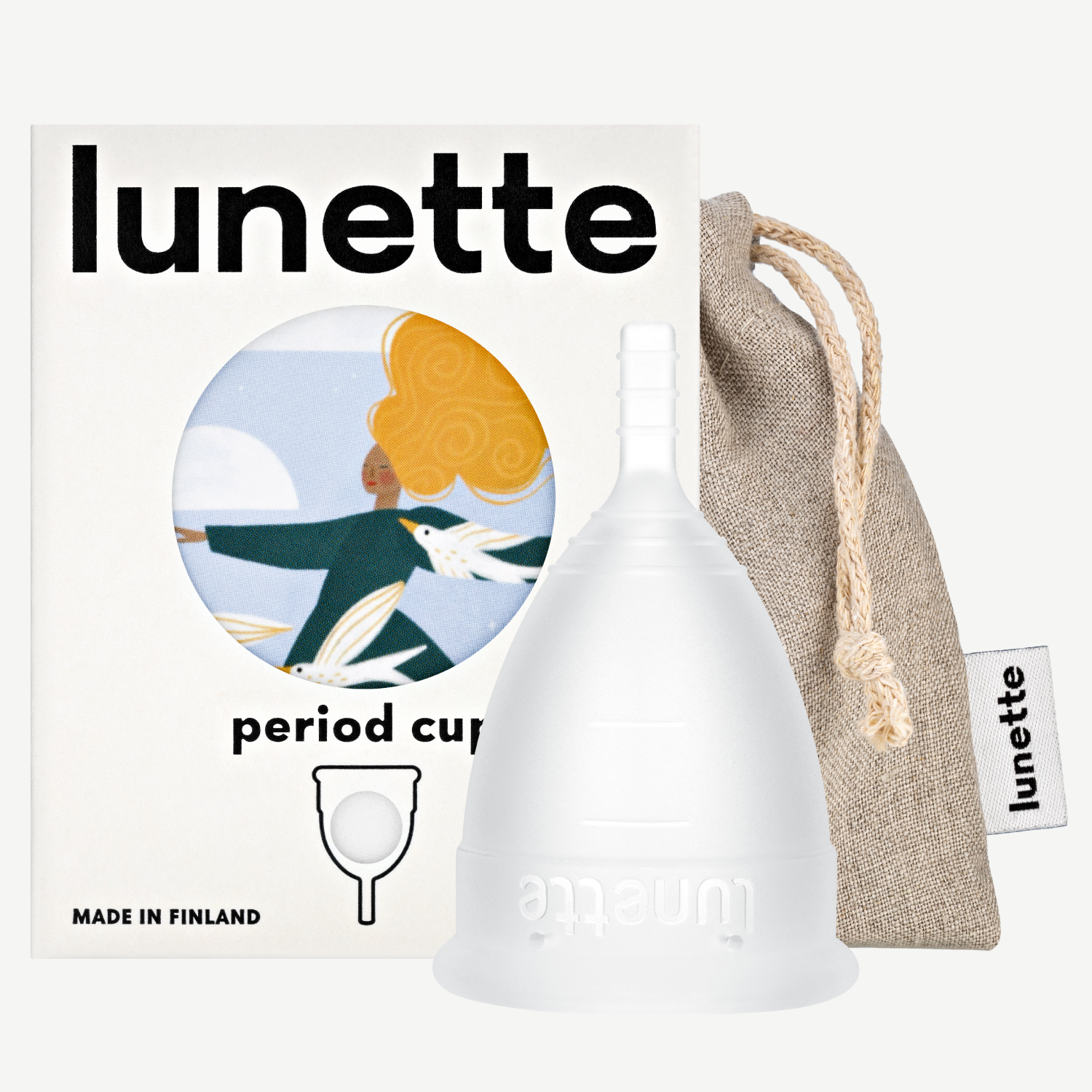 A white Lunette period cup displayed alongside its packaging box with a floral design and a linen storage pouch. The box includes the text 'period cup', 'made in Finland', and the brand name 'Lunette'.